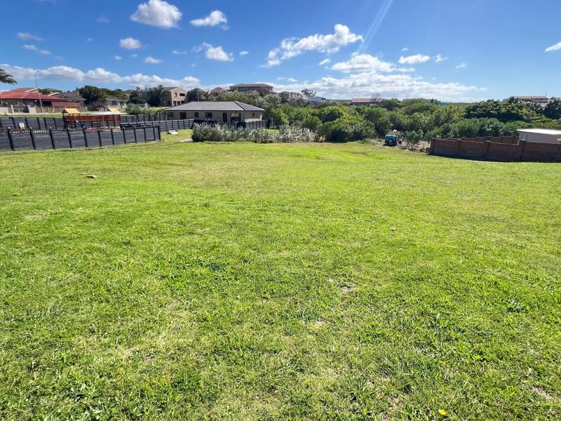 A spacious, level residential vacant plot featuring established grass cover and secure boundary fencing, situated within a developed neighborhood.
