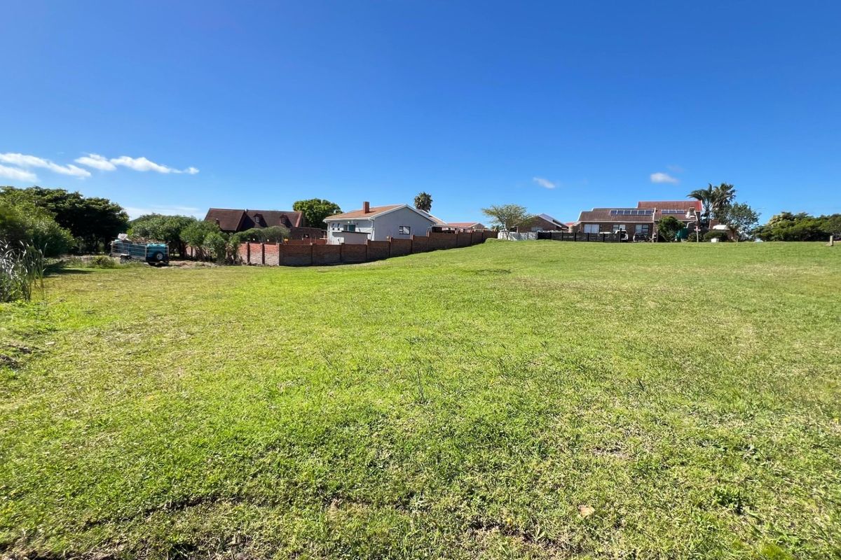 A wide-angle view of a vacant residential plot featuring a well-maintained grass lawn and surrounding boundary walls in a quiet neighborhood setting.