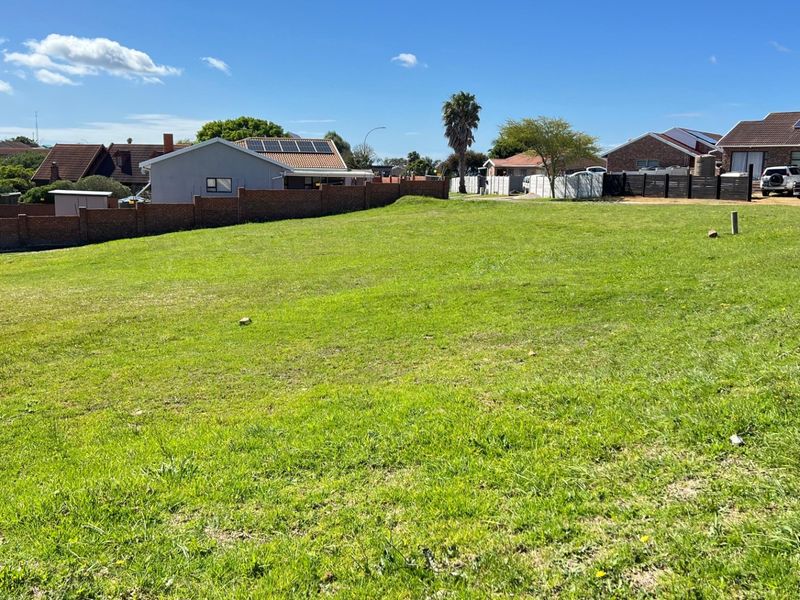 A vacant residential plot featuring a well-maintained grassed surface and a brick boundary wall, situated in an established neighbourhood.