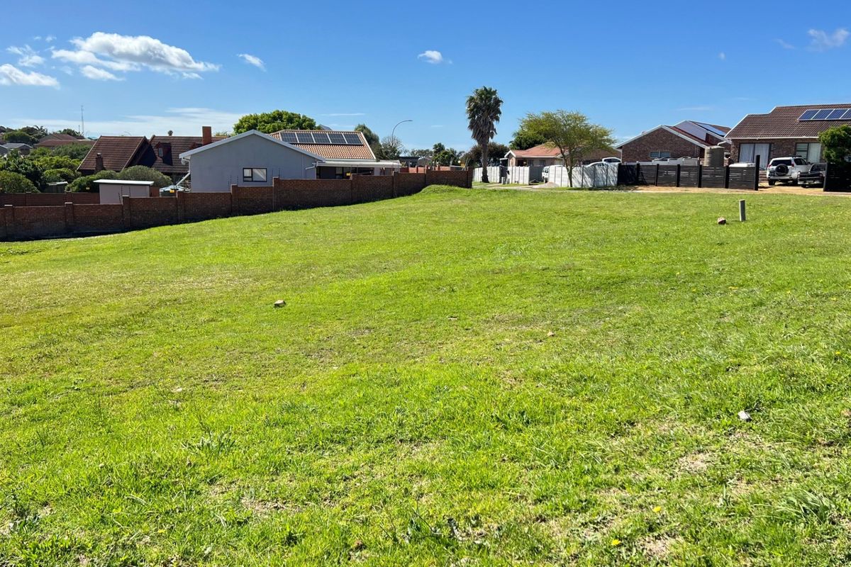 A vacant residential plot featuring a well-maintained grassed surface and a brick boundary wall, situated in an established neighbourhood.