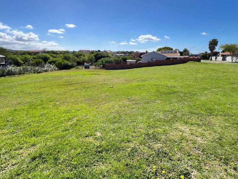 A spacious, level residential vacant plot featuring established grass cover and surrounding boundary walls in a quiet neighborhood setting.
