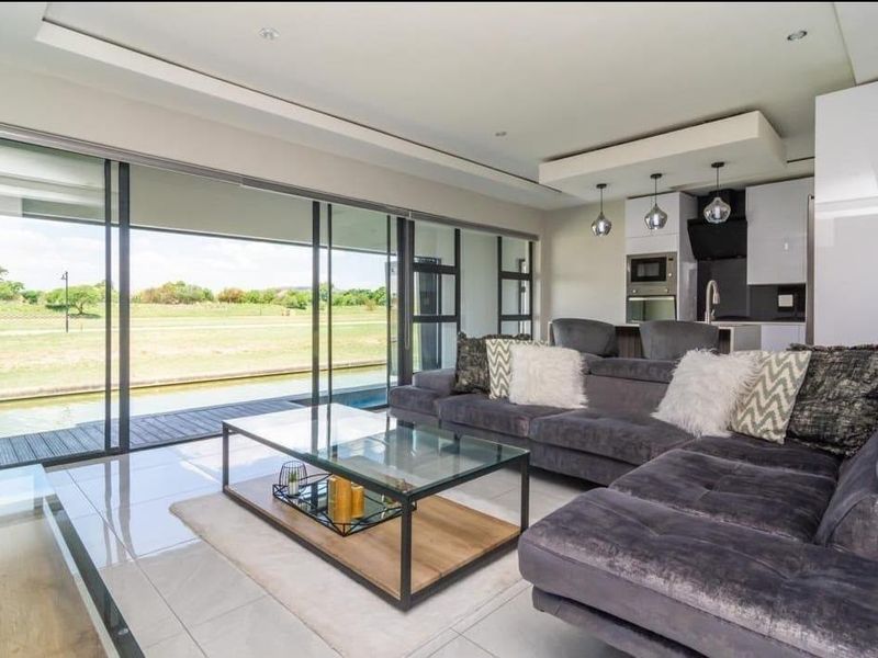 Modern open-plan living area featuring sleek kitchen cabinetry, large sliding glass doors, and seamless indoor-outdoor flow to the patio and pool area.