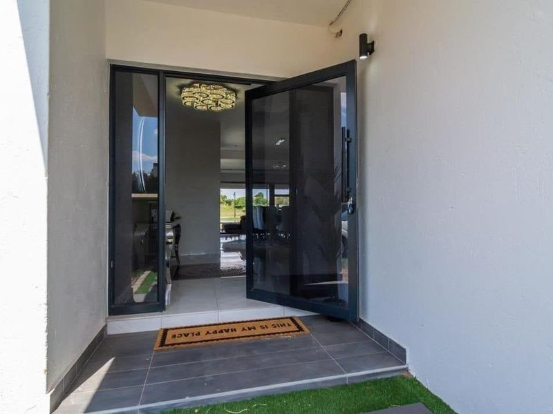 Modern entrance featuring a large pivot front door with glass sidelight, leading into a bright and open interior space.