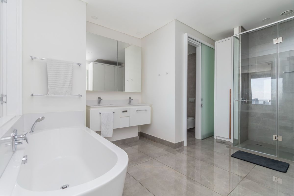 Modern bathroom featuring a double vanity, freestanding bathtub, glass-enclosed shower, and high-quality tiled finishes in a clean, contemporary design.