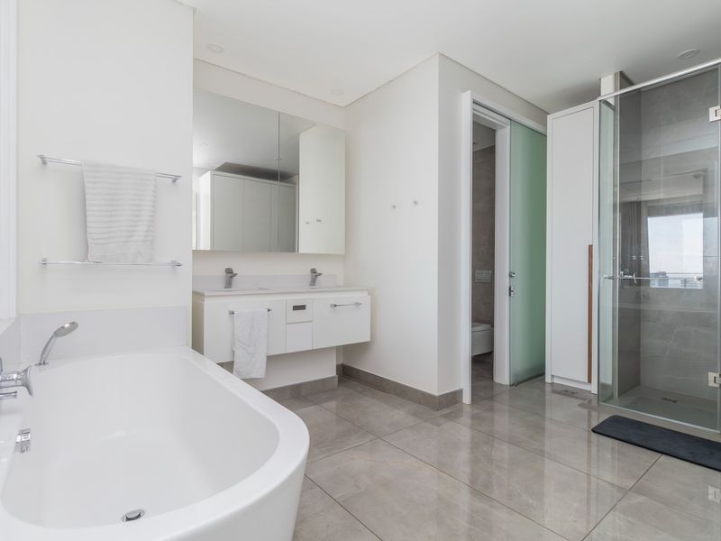 Modern bathroom featuring a double vanity, freestanding bathtub, glass-enclosed shower, and high-quality tiled finishes in a clean, contemporary design.