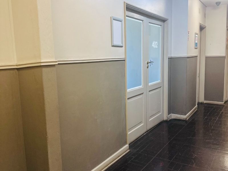 A functional office hallway featuring dark flooring, two-tone wall paint, and access to office suite 402.