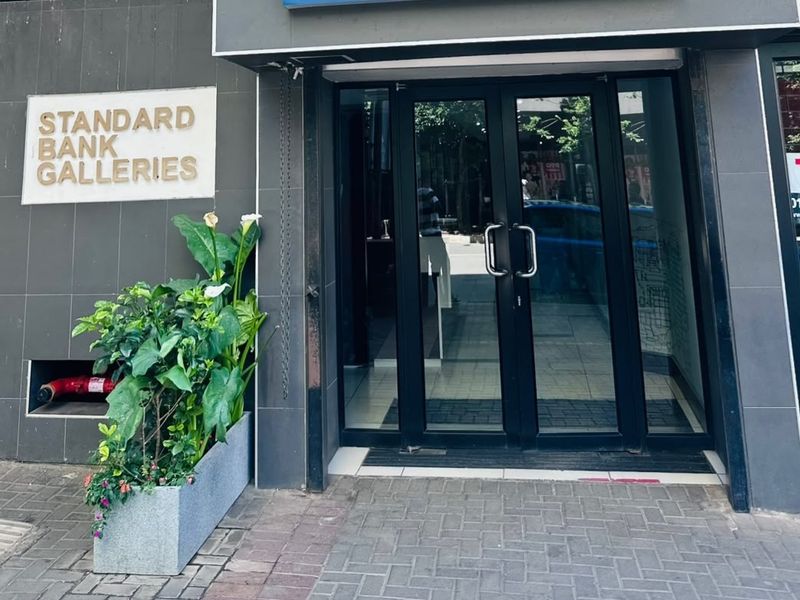 Main entrance to the Standard Bank Galleries office building, featuring modern glass double doors and a clean tiled exterior facade.