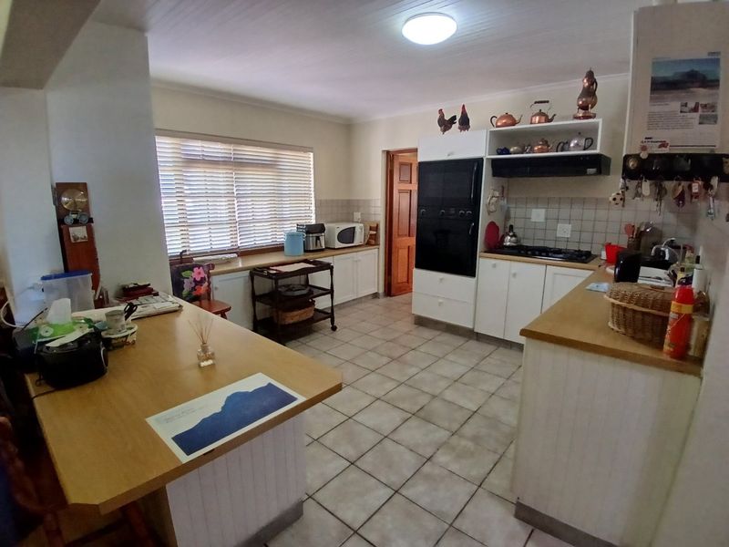 A functional kitchen featuring built-in cabinetry, a gas hob, an integrated oven, and tiled flooring with a breakfast counter area.