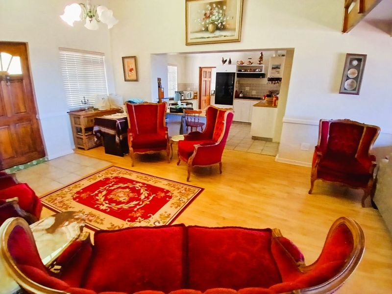 Open plan living area featuring laminate flooring and a connected kitchen with built-in cabinetry and tiled floors.