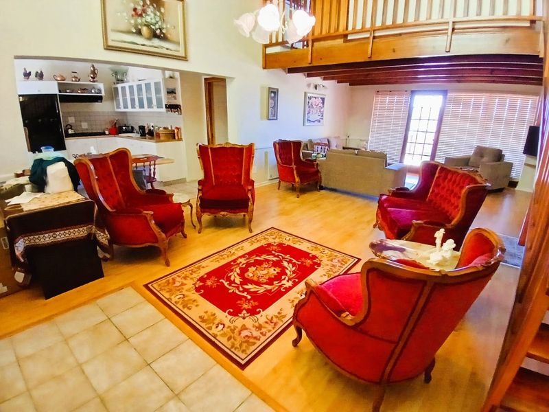 Spacious open-plan living area featuring laminate flooring, exposed timber beams, a mezzanine level, and an integrated kitchen with built-in cabinetry.