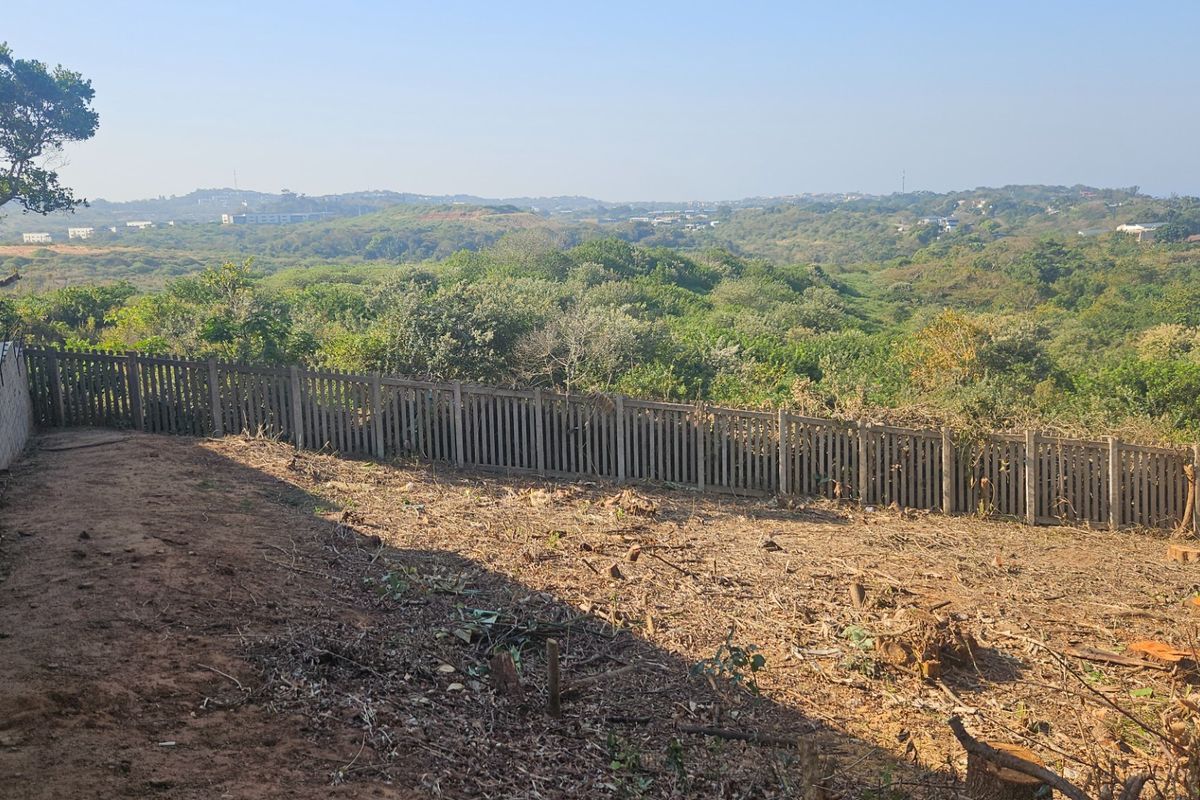 A vacant residential plot featuring a perimeter fence and retaining wall, offering expansive views of the surrounding natural landscape.