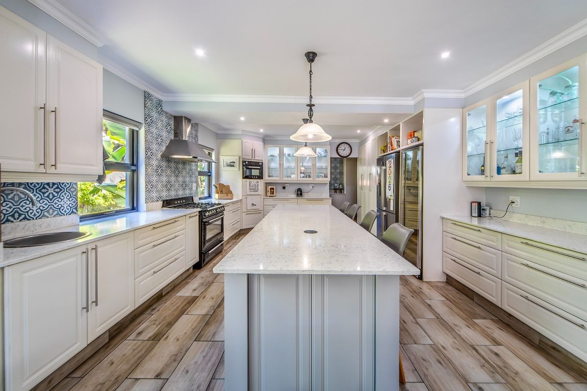 A modern, well-appointed kitchen featuring a large central island, quartz countertops, gas range, and extensive custom cabinetry with integrated lighting.