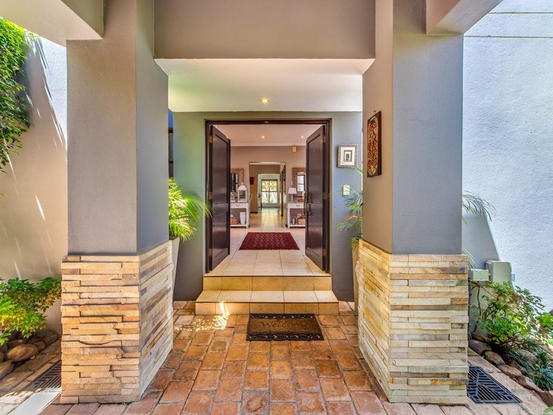 Inviting front entrance featuring stone-clad pillars, brick paving, and double doors leading into a well-maintained interior hallway.