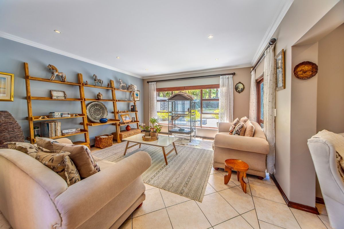 A bright and inviting living room featuring tiled flooring, recessed downlights, and large windows that provide ample natural light and garden views.