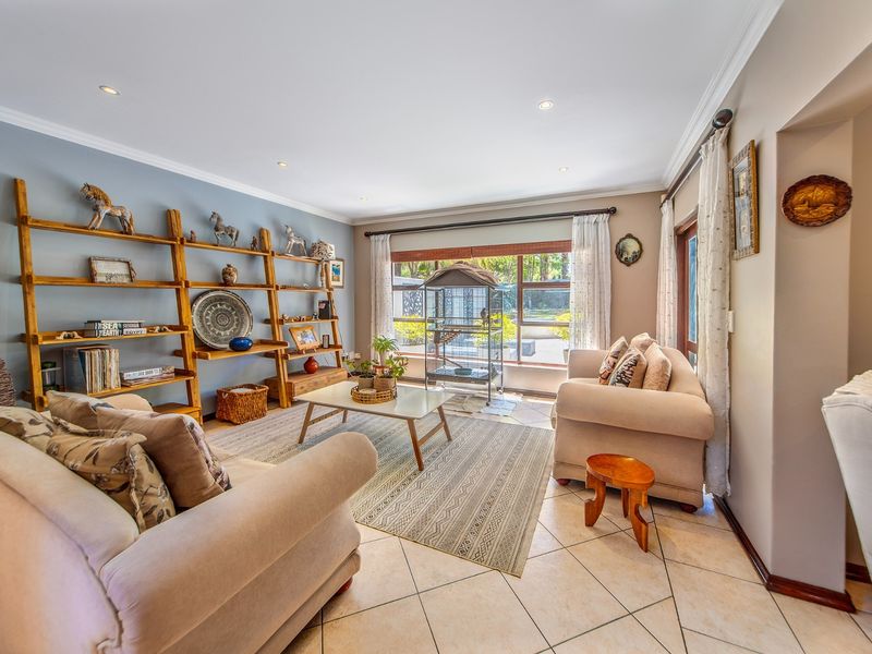 A bright and inviting living room featuring tiled flooring, recessed downlights, and large windows that provide ample natural light and garden views.