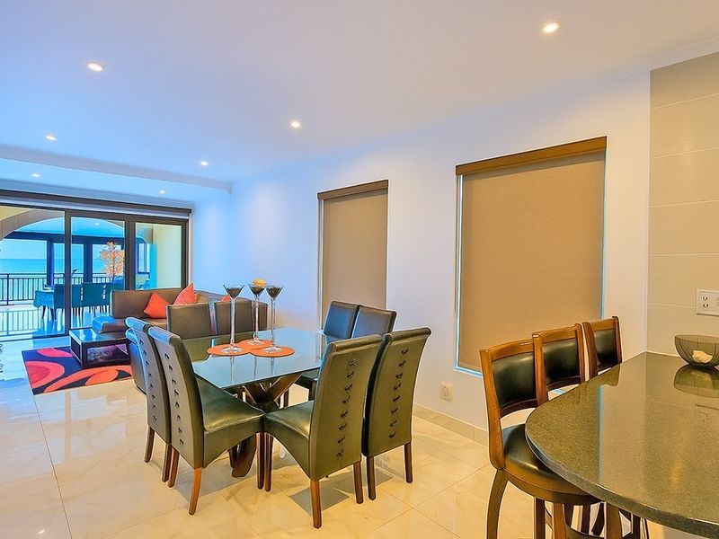 Spacious open-plan living and dining area featuring tiled floors, recessed lighting, and seamless access to a private balcony through large sliding glass doors.