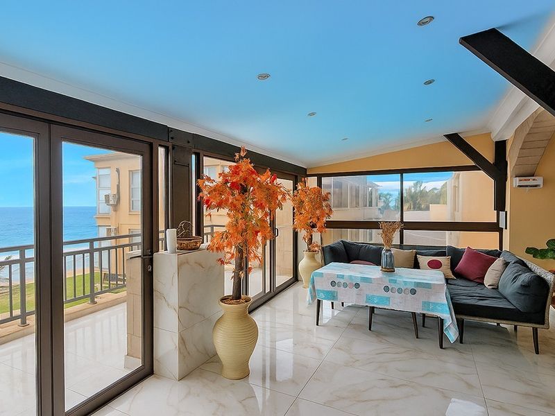 Enclosed balcony featuring large sliding glass doors, polished marble-look floor tiles, and recessed lighting, offering expansive ocean views.