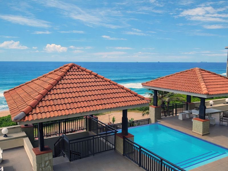 Stunning outdoor pool area featuring a covered gazebo, tiled patio, and direct ocean views, perfect for coastal living and relaxation.