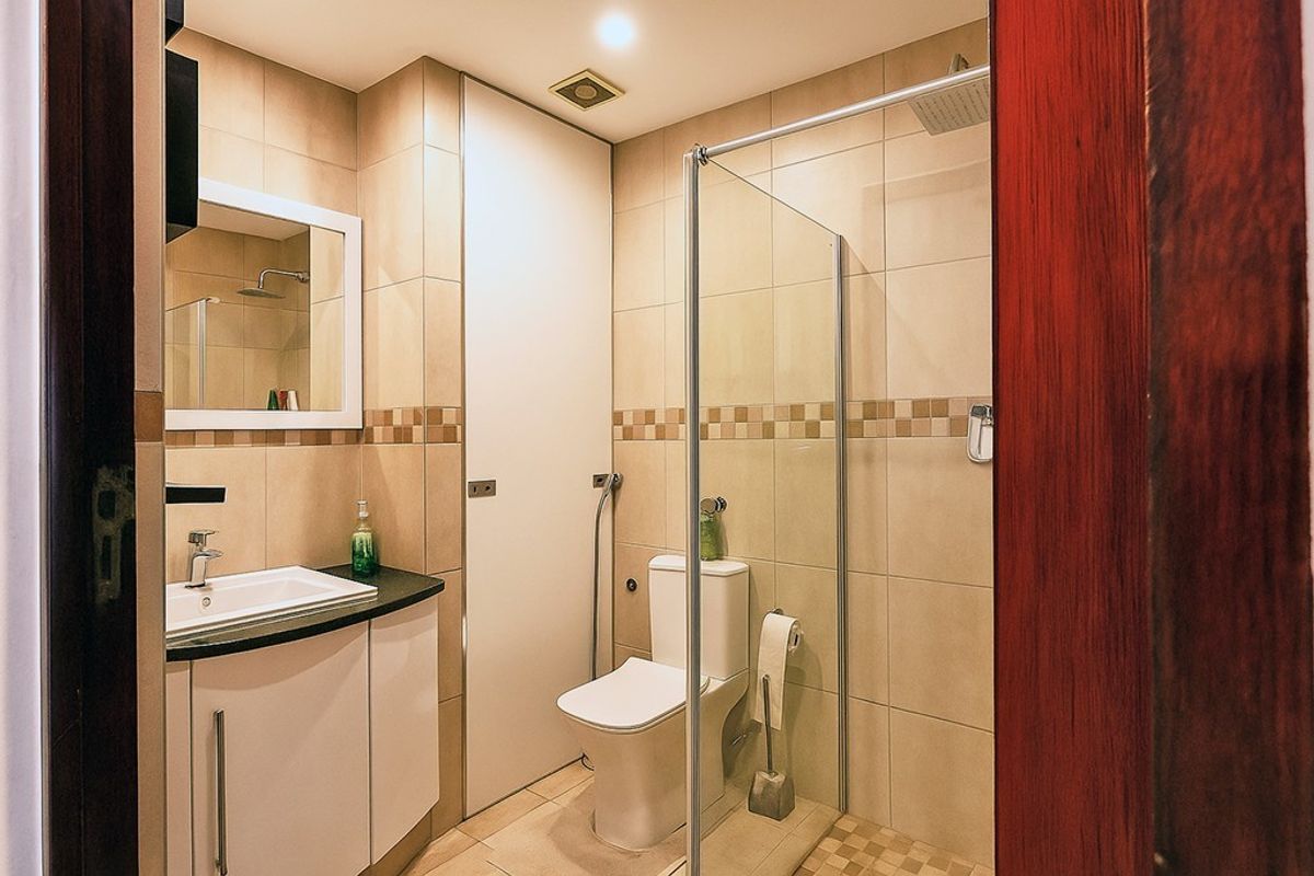 A modern bathroom featuring a glass-enclosed shower, vanity with basin, and neutral wall tiling.