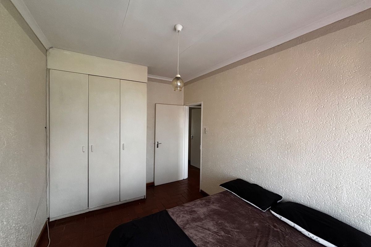A bedroom featuring built-in cupboards, tiled flooring, and coved ceilings, offering a functional space ready for cosmetic updates.