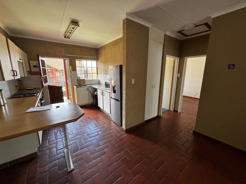 A functional kitchen featuring built-in cabinetry, a hob, and oven, with direct access to an outdoor area and tiled flooring throughout.