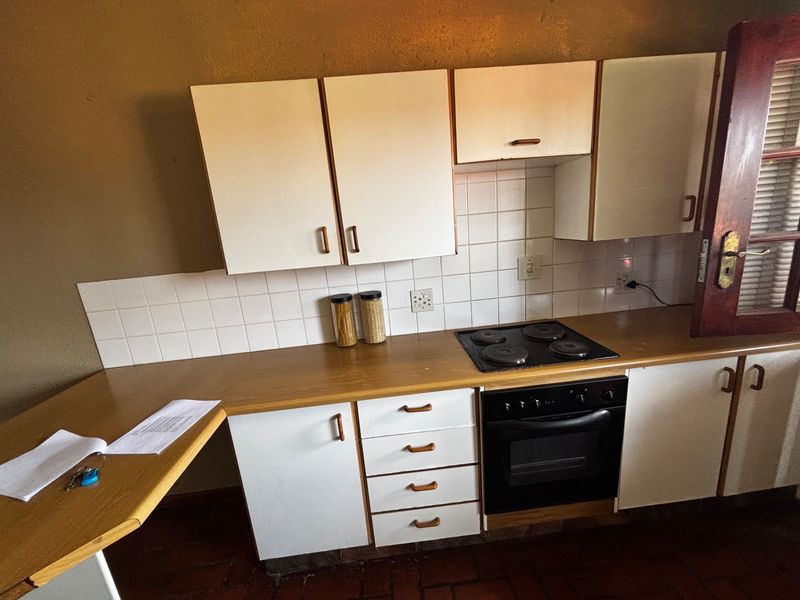 A functional kitchen featuring white cabinetry, a laminate countertop, tiled backsplash, and a built-in electric oven and hob.