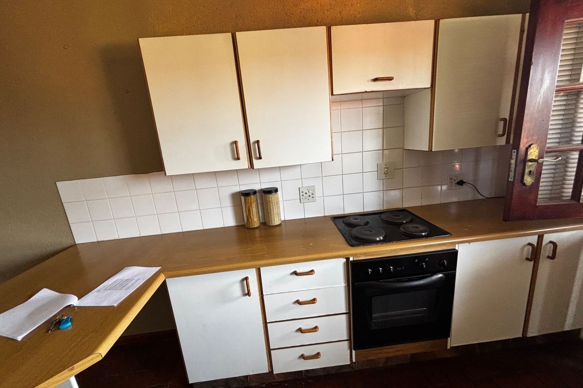 A functional kitchen featuring white cabinetry, a laminate countertop, tiled backsplash, and a built-in electric oven and hob.