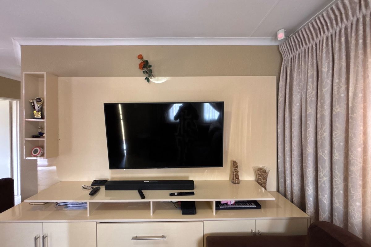 A living room featuring a built-in media wall unit with integrated cabinetry and storage, complemented by floor-to-ceiling curtains.