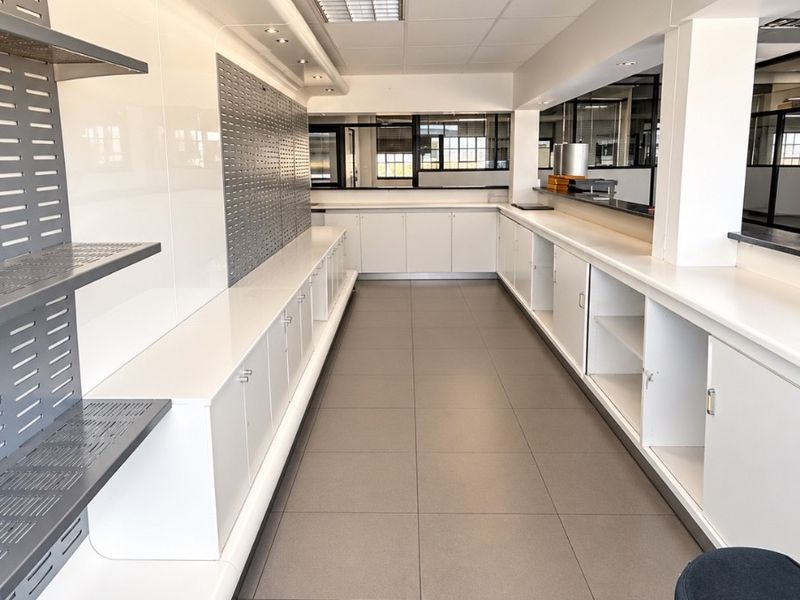 A clean, modern commercial kitchen or service area featuring extensive built-in cabinetry, tiled flooring, and integrated recessed lighting throughout the workspace.