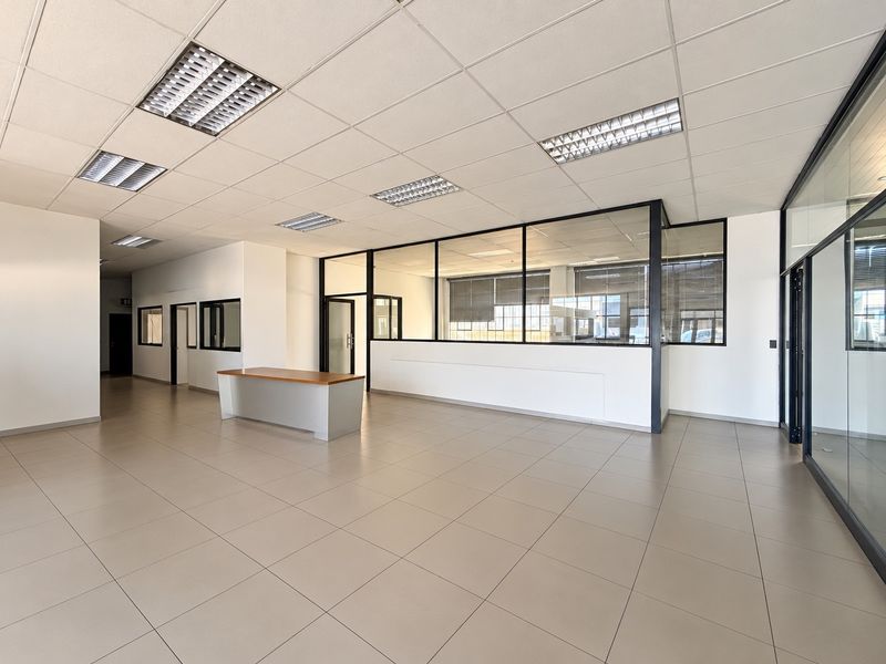 A spacious, modern commercial office area featuring tiled floors, suspended ceilings with recessed lighting, and glass partition walls for a professional, open-plan workspace.