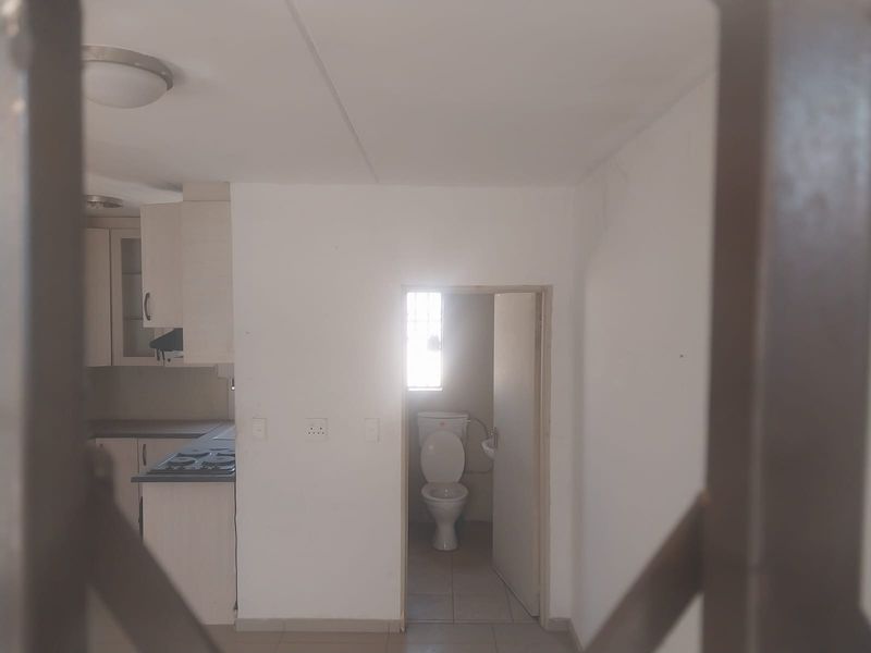 Open plan living area featuring a compact kitchen with built-in cabinetry and a separate bathroom with a toilet and basin.