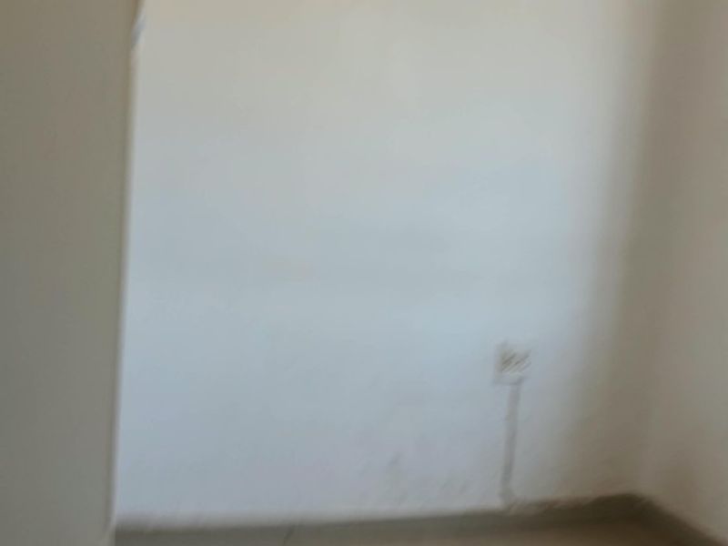 An empty bedroom featuring tiled flooring and plain walls, requiring cosmetic updates and fresh paint to enhance its appeal.