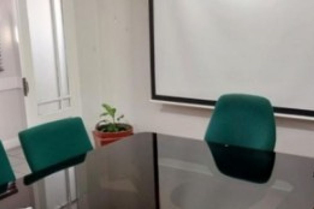 A functional office space featuring a wall-mounted projector screen and glass door access.