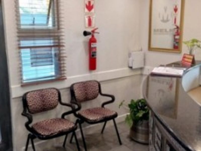 A professional office reception area featuring a built-in reception desk, tiled flooring, and safety equipment including a wall-mounted fire extinguisher.