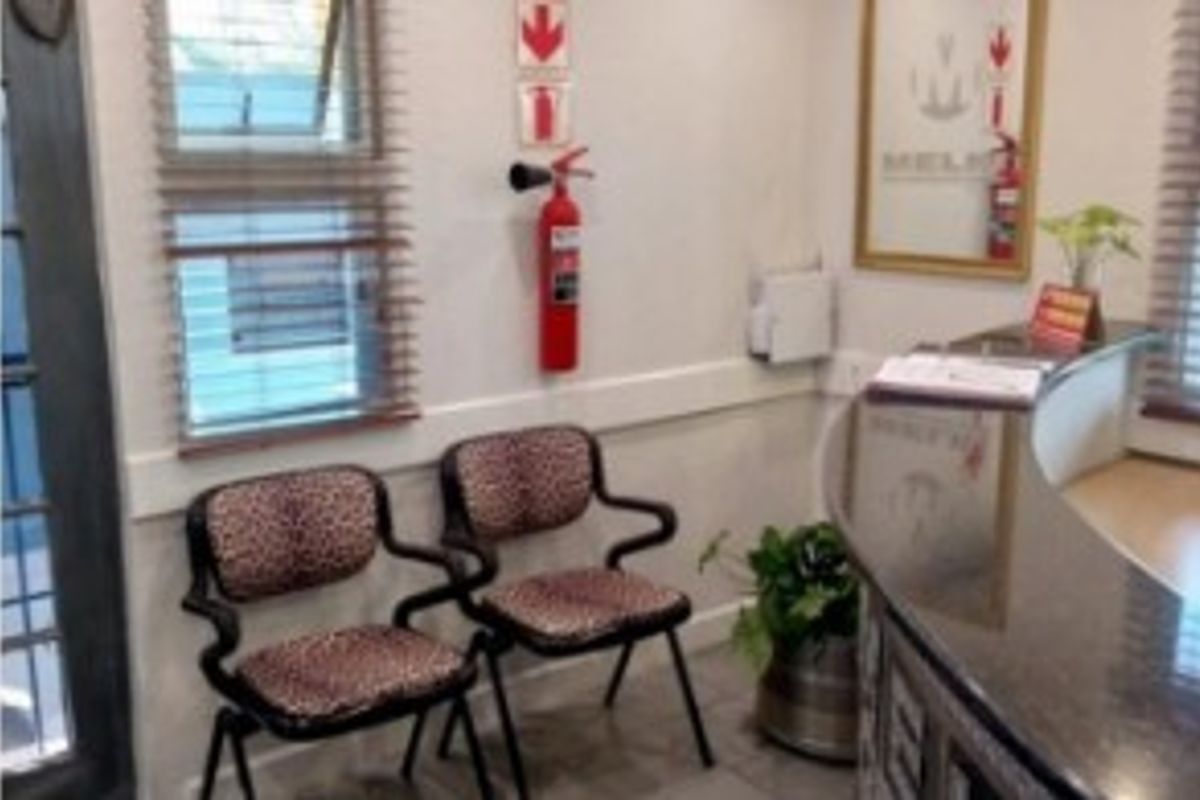 A professional office reception area featuring a built-in reception desk, tiled flooring, and safety equipment including a wall-mounted fire extinguisher.