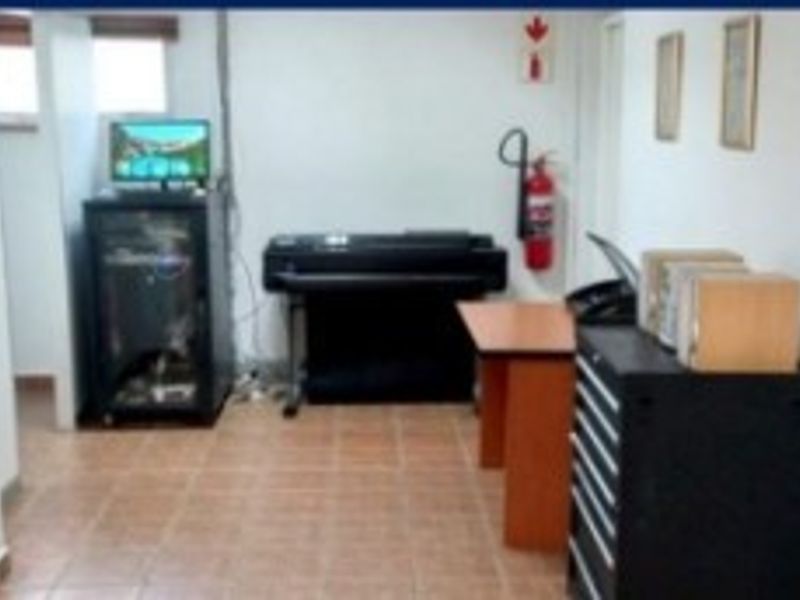 A functional office space featuring tiled flooring and a wall-mounted fire extinguisher, suitable for administrative or technical work.