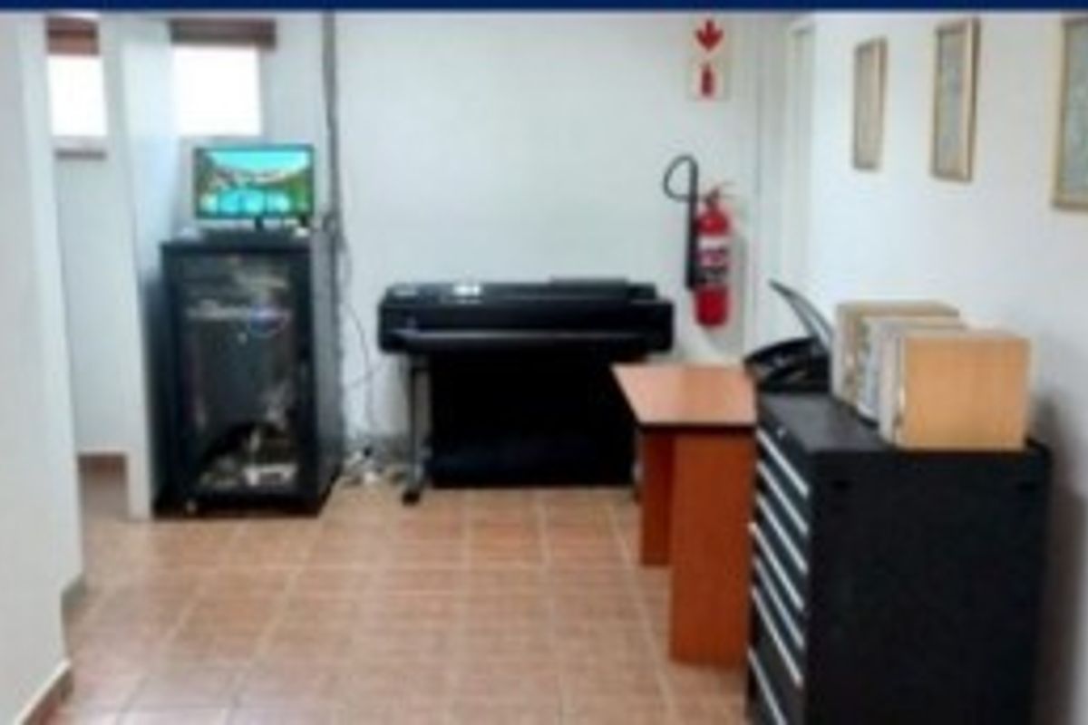 A functional office space featuring tiled flooring and a wall-mounted fire extinguisher, suitable for administrative or technical work.