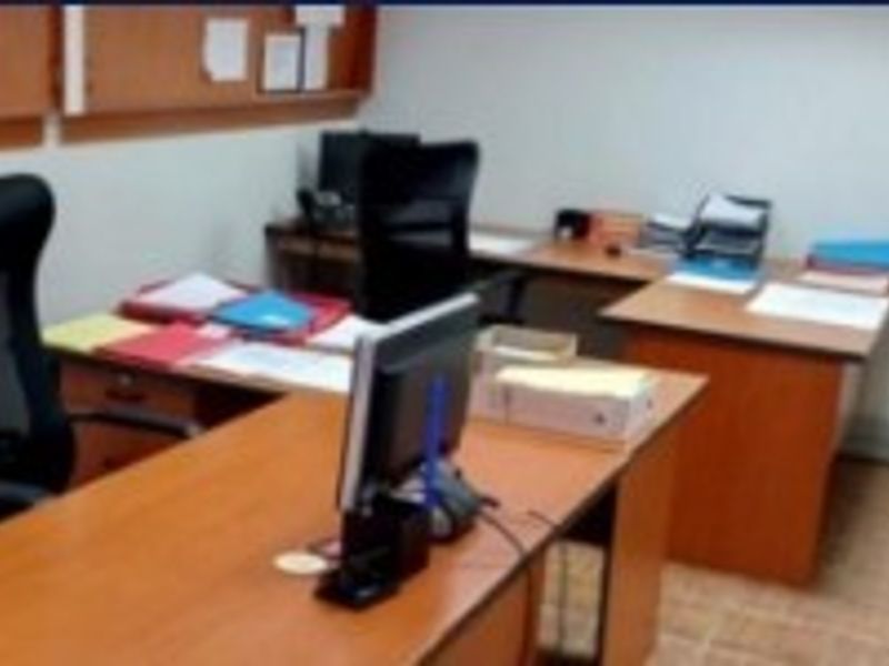 A functional office space featuring tiled flooring and a wall-mounted cork board, providing a practical environment for professional work.