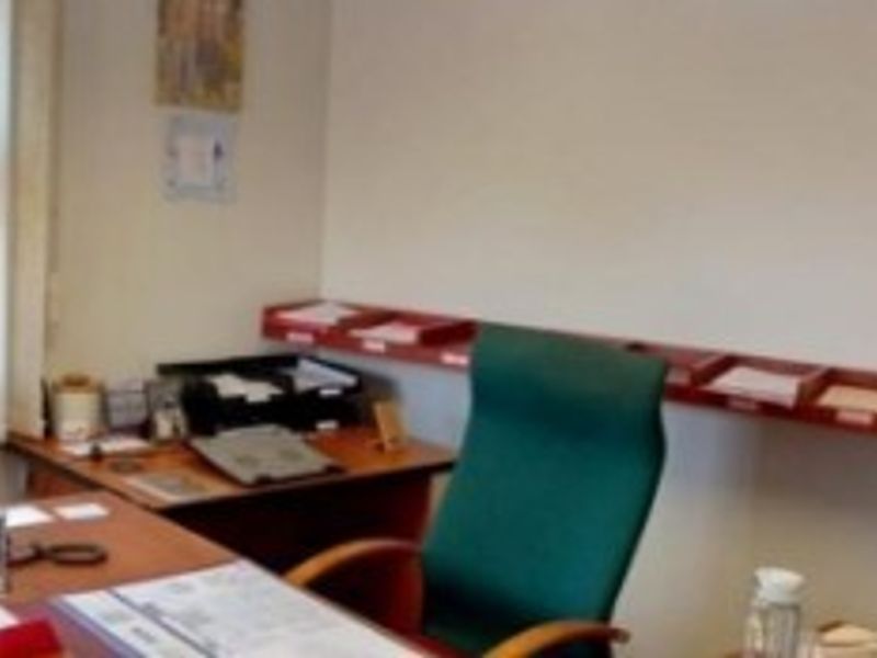 A functional office space featuring vertical window blinds and wall-mounted shelving units for organized storage.