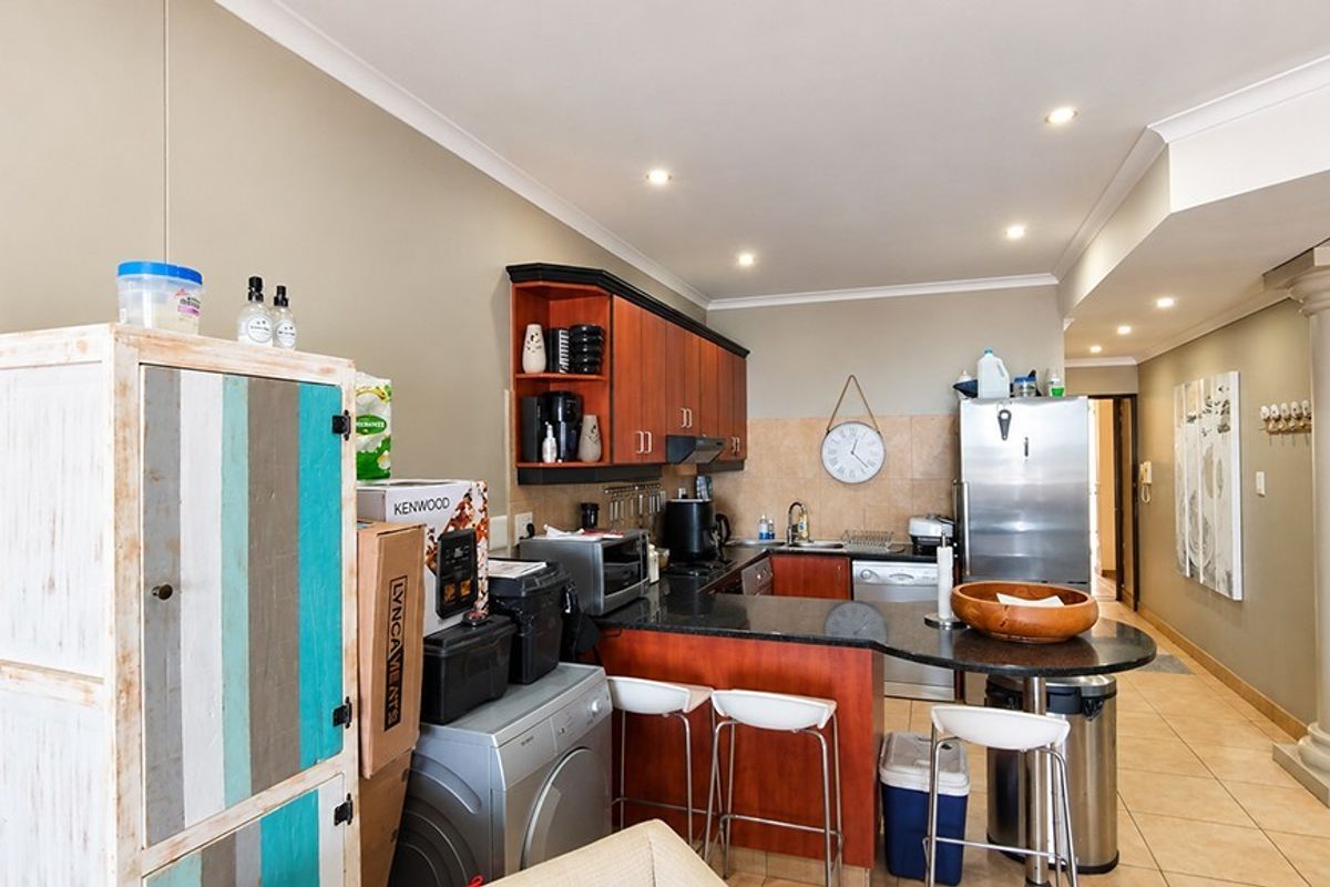 A functional kitchen featuring granite countertops, dark wood cabinetry, tiled flooring, and a breakfast bar area with recessed lighting.