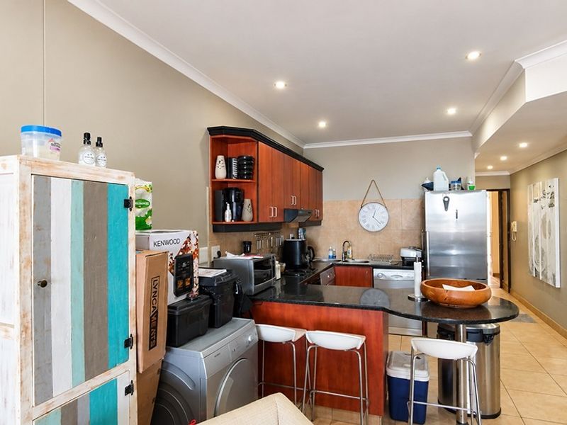 A functional kitchen featuring granite countertops, dark wood cabinetry, tiled flooring, and a breakfast bar area with recessed lighting.