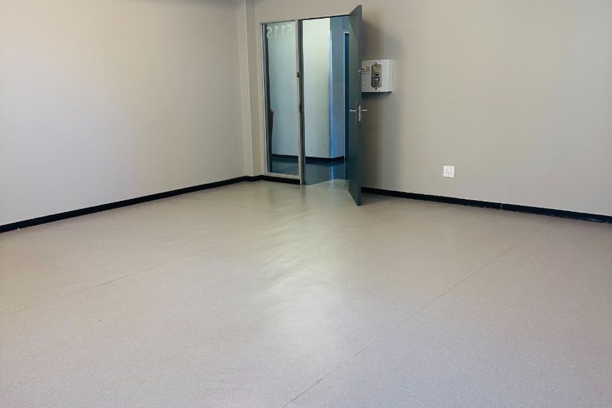 A clean, vacant office space featuring neutral walls, durable vinyl flooring, exposed industrial-style fire sprinkler piping, and an integrated intercom system.