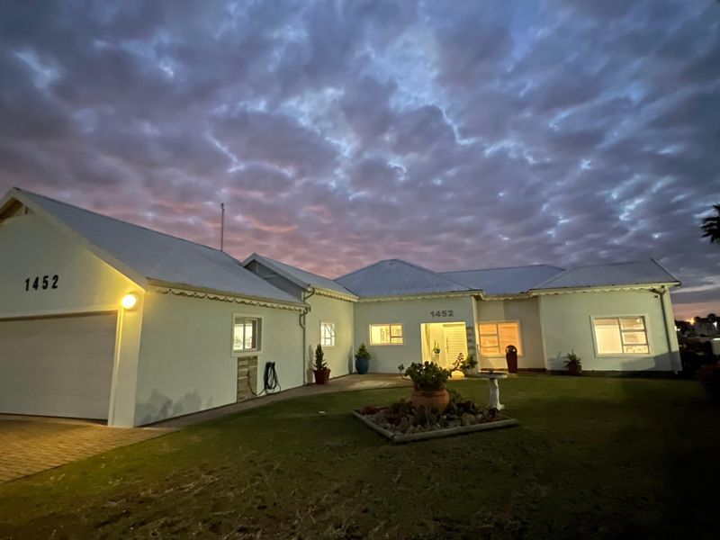 A well-maintained single-story residential home featuring a paved driveway, attached garage, and exterior lighting, captured during twilight.
