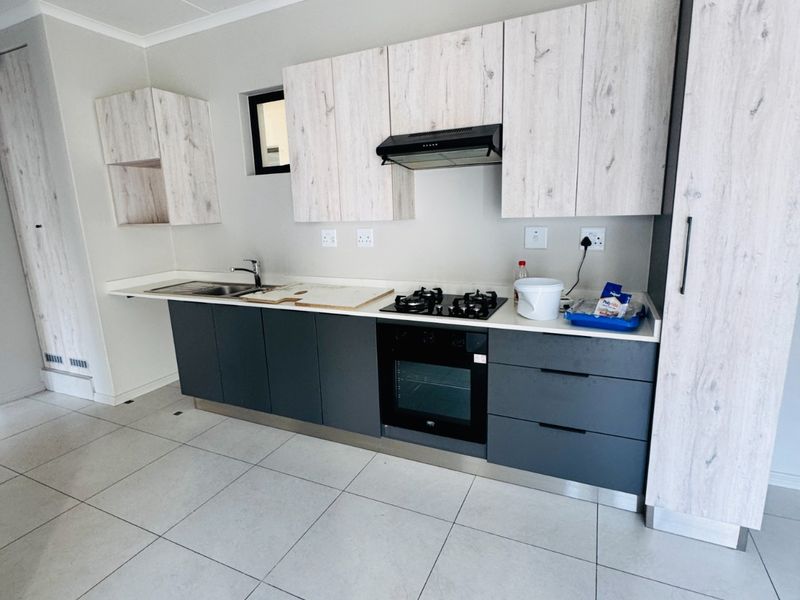 Modern kitchen featuring two-tone cabinetry, stone countertops, built-in gas hob, electric oven, extractor fan, and tiled flooring.