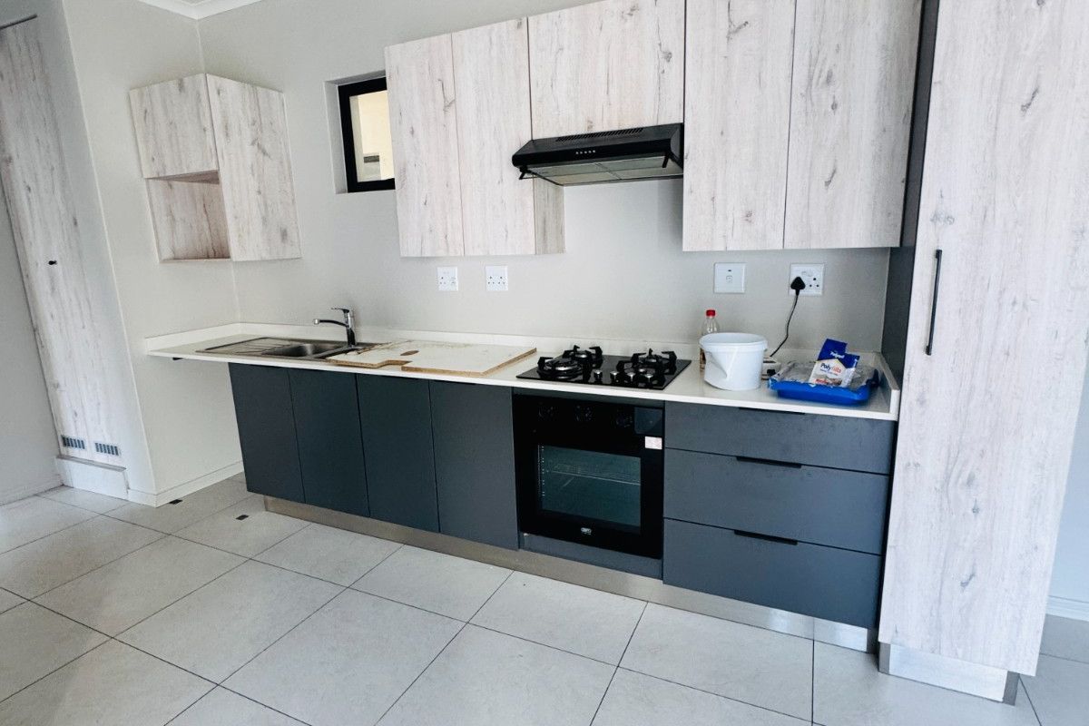 Modern kitchen featuring two-tone cabinetry, stone countertops, built-in gas hob, electric oven, extractor fan, and tiled flooring.