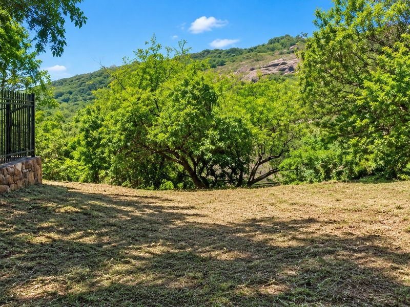 A scenic view of the surrounding landscape featuring a stone retaining wall and metal perimeter fencing on the property boundary.