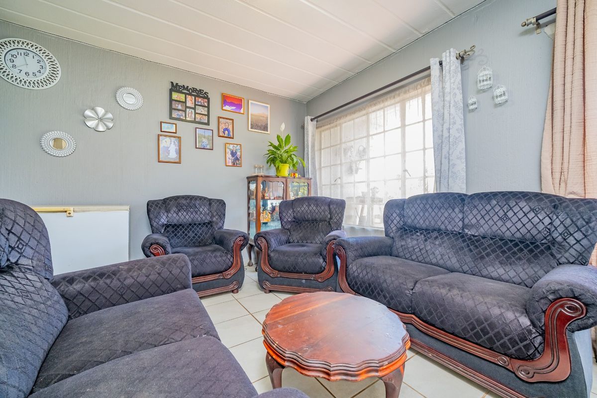 A comfortable living room featuring tiled flooring, a large window allowing natural light, and textured wall finishes.