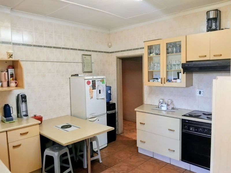 A functional kitchen featuring tiled walls, built-in cabinetry, an integrated oven with hob, and tiled flooring, offering a practical layout for daily meal preparation.