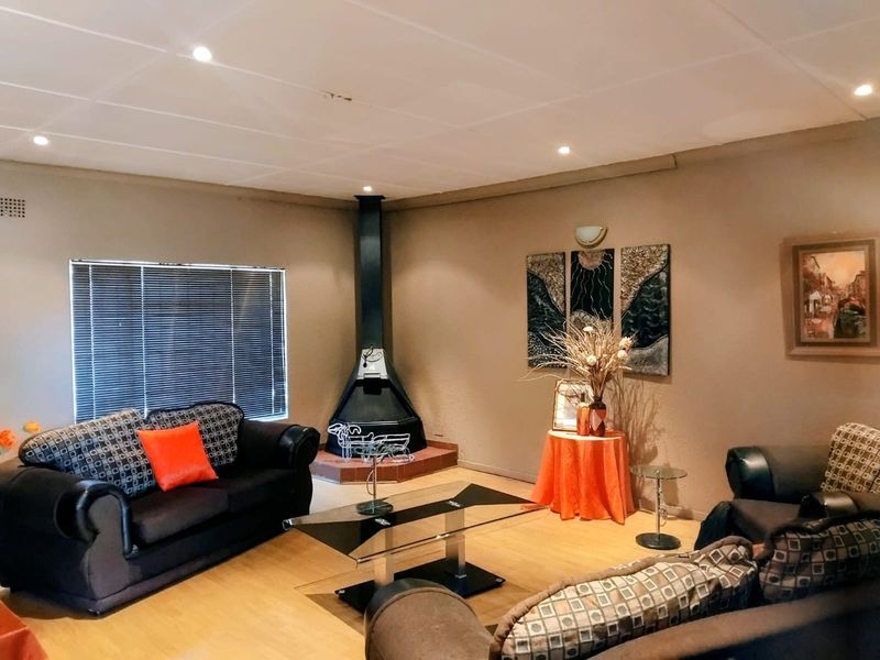 A comfortable living room featuring a corner fireplace, laminate flooring, and recessed ceiling lighting, creating a warm and inviting atmosphere.