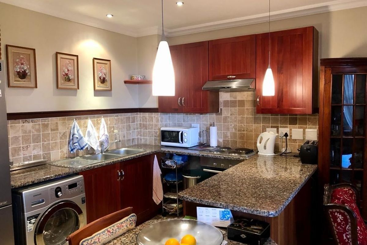 A functional kitchen featuring warm-toned wooden cabinetry, granite countertops, a tiled backsplash, and integrated appliances, offering a classic and practical cooking space.